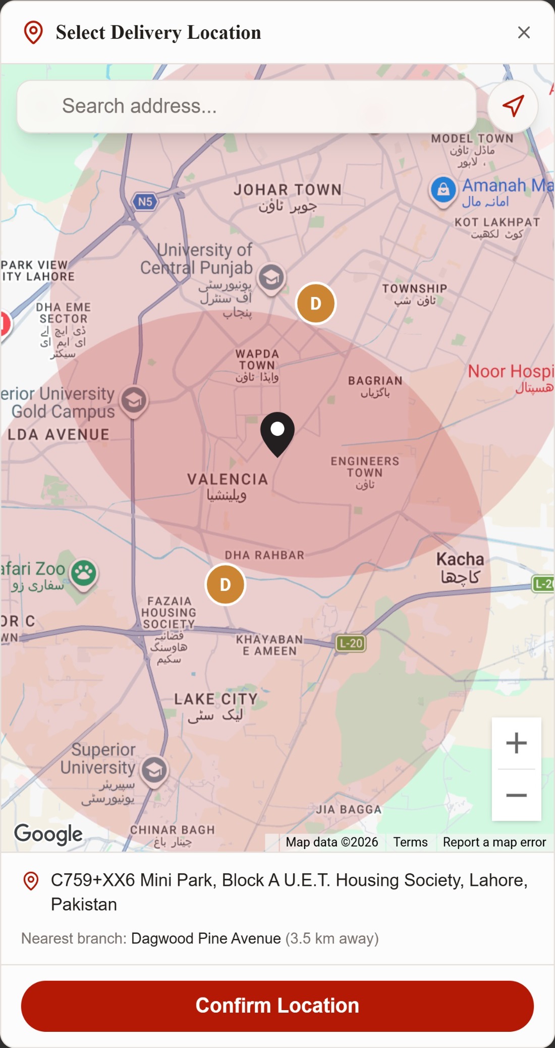 Select delivery location modal with an address search field over a live Lahore map, a shaded delivery radius drawn around each of the two branch markers, a dropped pin, the resolved street address, the nearest branch and its distance, and a confirm location button